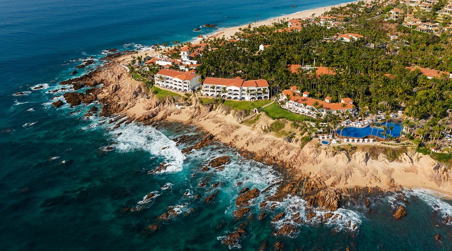 One and Only Palmilla Los Cabos luxury beachfront resort with swimmable beach and palm-lined grounds.
