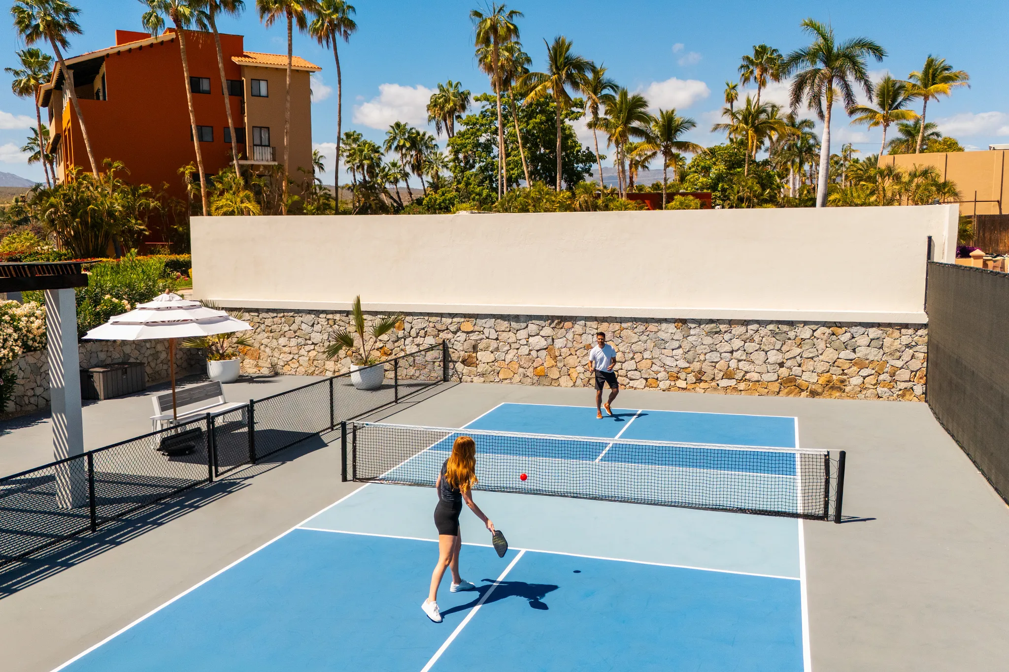Guests playing pickleball on outdoor court at Zoëtry Casa del Mar Los Cabos surrounded by tropical landscaping.